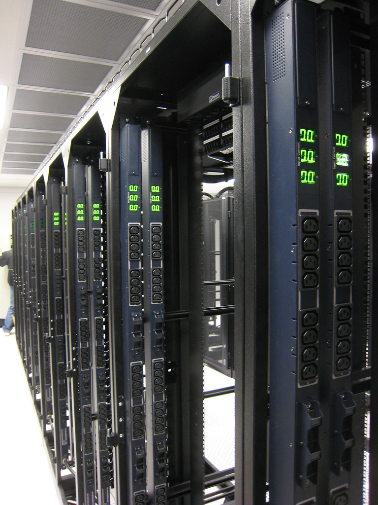 Sala de servidores moderna con racks y luces LED, representando el hosting web