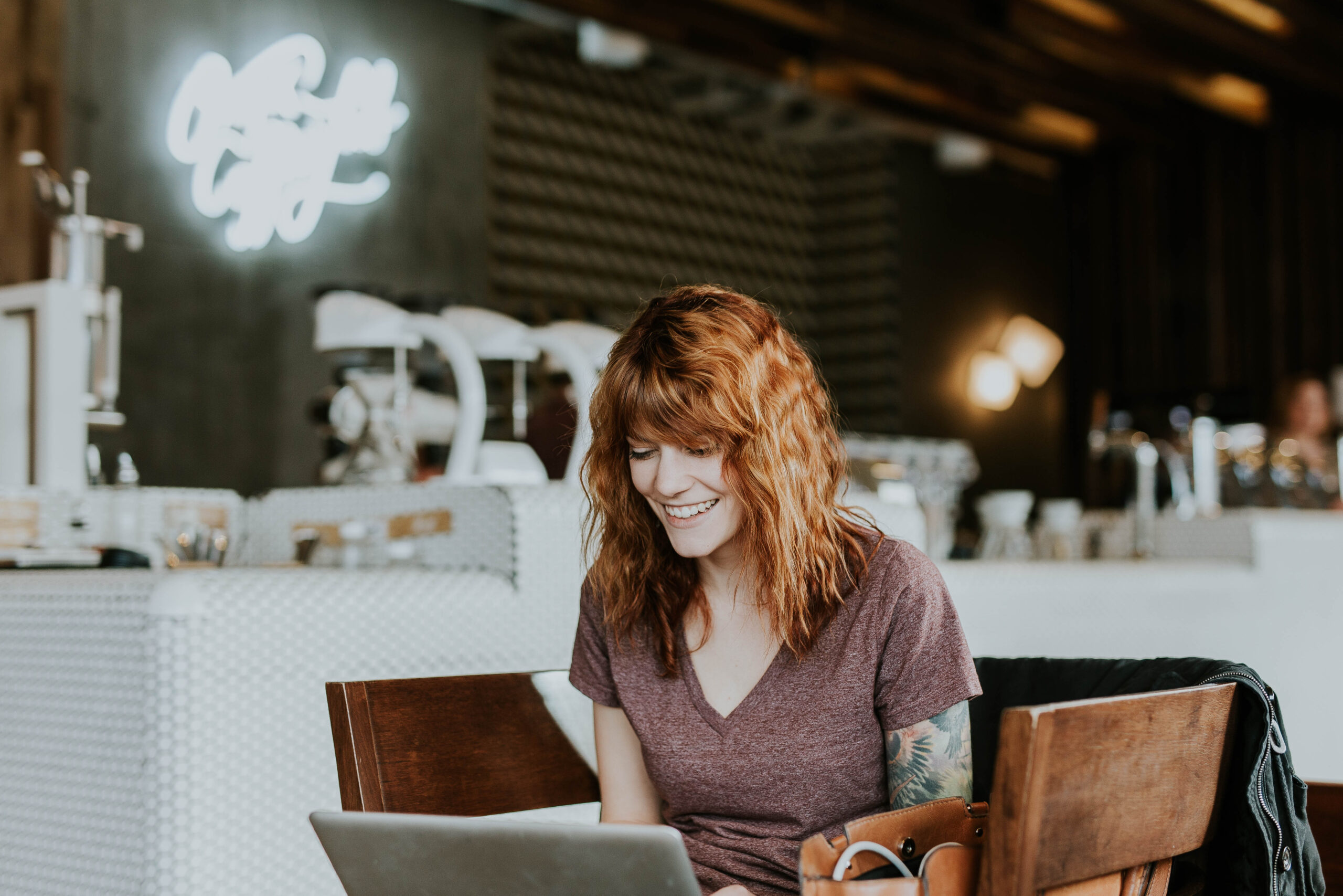 Mujer sonriendo usando portatil en una cafeteria