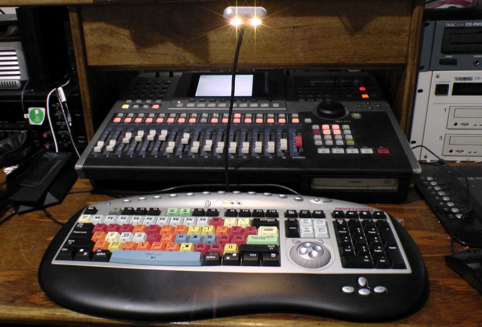 Teclado con teclas de colores para edicion de video junto a una mesa de mezclas