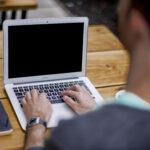 Persona escribiendo en un portátil, revisando un texto